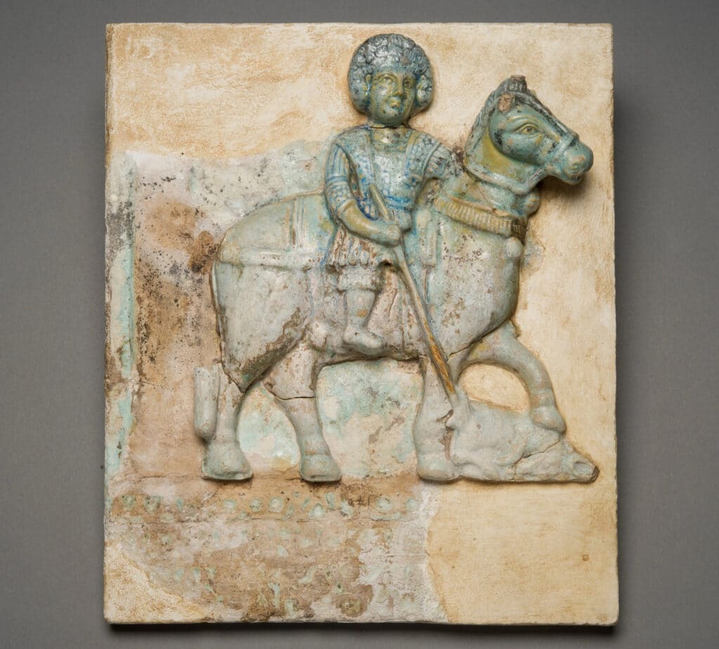 Relief tile depicting a horse rider (Horus) spearing an oryx (Seth). Roman Period, 300-395 AD. Faience. [ECM 2166];